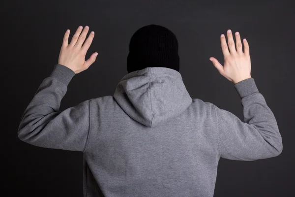 Back view of man in black mask holding hands up over grey — Stock Photo, Image