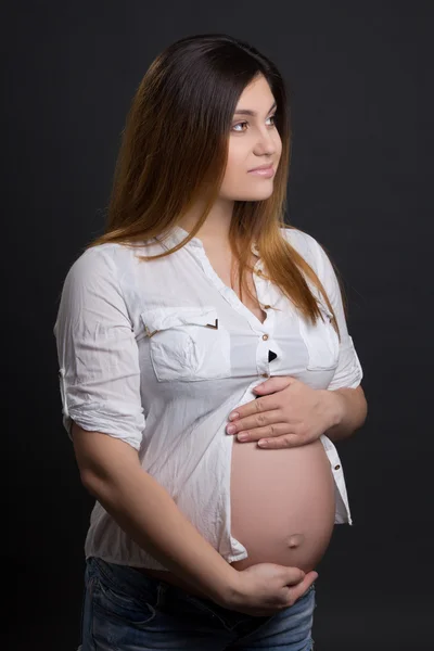 Joven hermosa mujer embarazada posando sobre gris —  Fotos de Stock