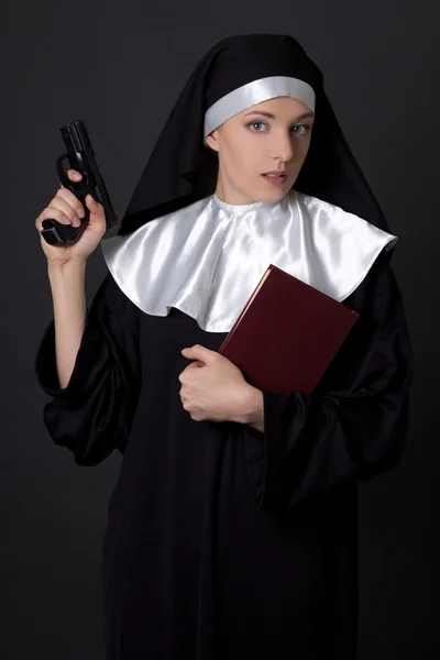 Woman nun with bible and gun over grey — Stock Photo, Image