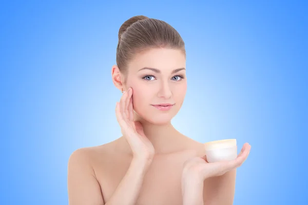 Young beautiful smiling woman with cream bottle over blue — Stock Photo, Image