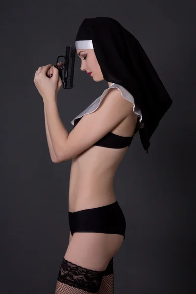 Sexig kvinna nunna i underkläder med pistol över grå — Stockfoto