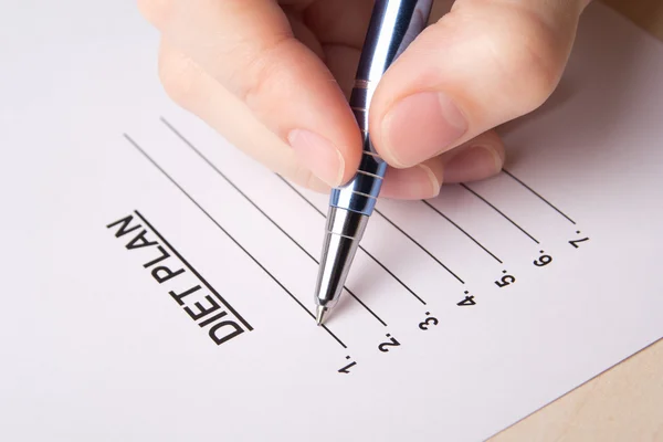 Vrouwelijke hand vullen haar dieetplan met pen — Stockfoto