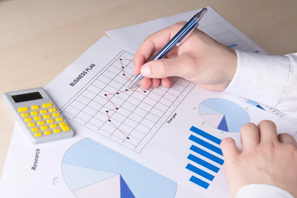 Hands with pen and business report on table — Stock Photo, Image