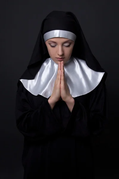 Jovem bonita freira reza sobre cinza — Fotografia de Stock