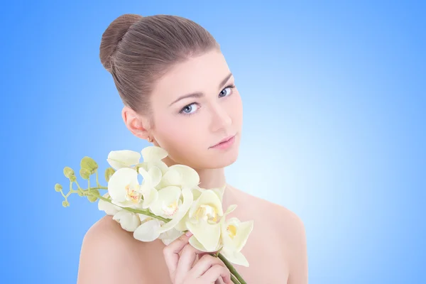 Retrato de uma jovem mulher bonita com flor orquídea sobre azul — Fotografia de Stock