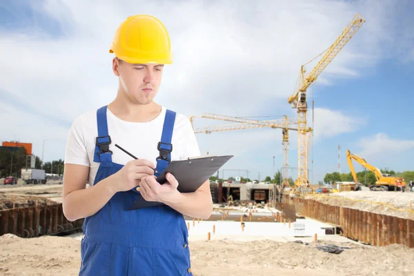 Porträtt av ung vacker man i builder uniform med clipboar — Stockfoto