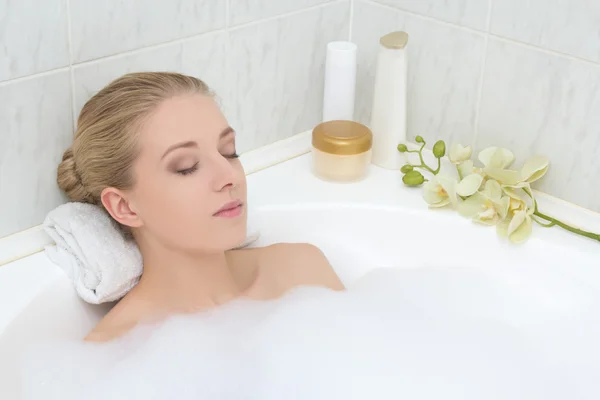 Jeune femme relaxant dans le bain avec mousse — Photo