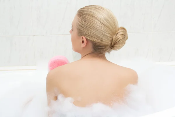 Back view of woman relaxing in bath and washing herself — Stock Photo, Image
