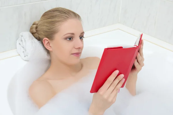 Woman relaxing in bath and reading book — Stock Photo, Image