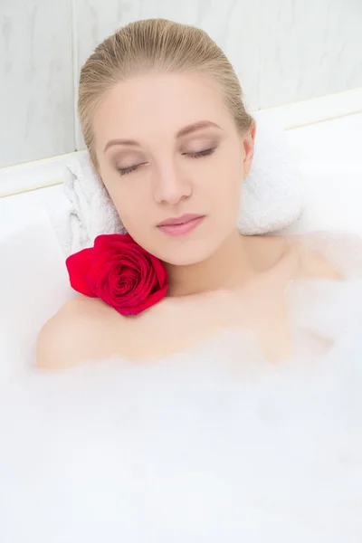Beautiful woman relaxing in bath with red flower — Stock Photo, Image