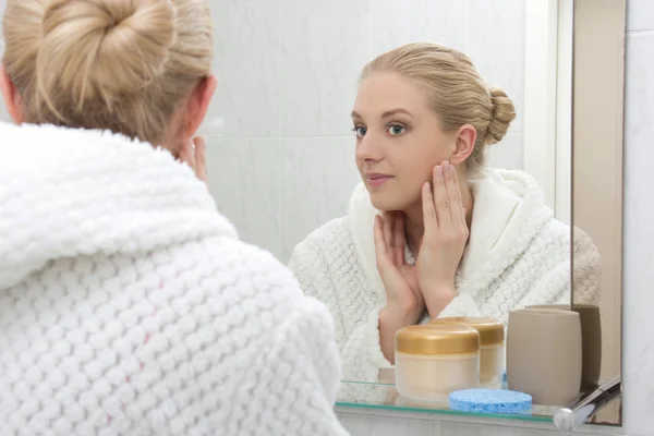 Young beautiful woman looking at mirror in bathroom — Stock Photo, Image