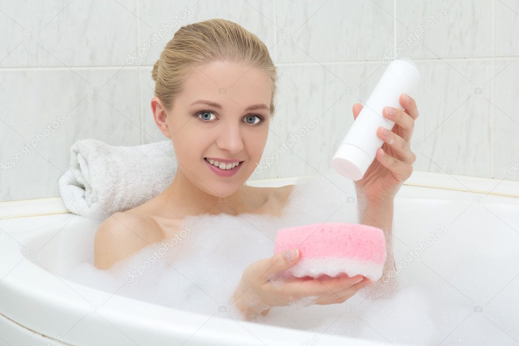 beautiful woman in bath with sponge and shower gel