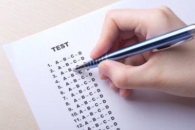 close up of hand filling test score sheet with answers clipart
