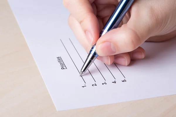 Close up of female hand filling priorities list with pen — Stock Photo, Image