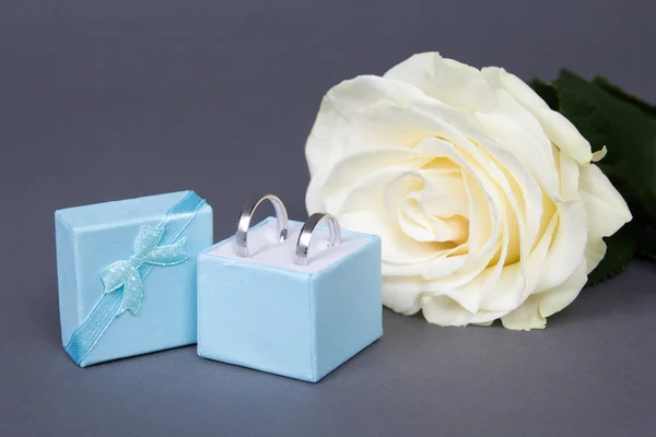 Hermosa flor de color de rosa blanca y anillos de boda en caja azul sobre g — Foto de Stock