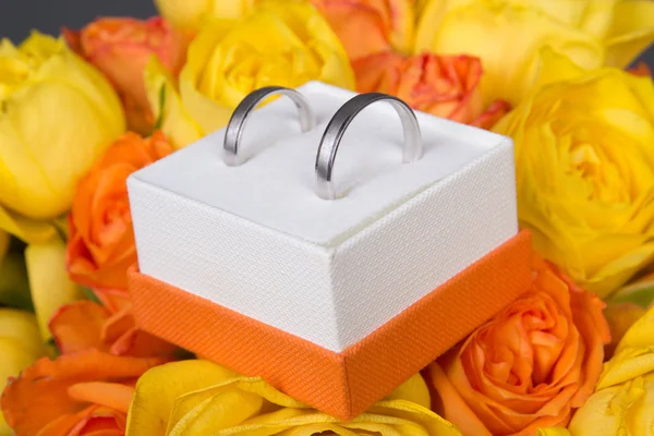 Ramo de flores color de rosa amarillas y naranjas y anillos de boda en b — Foto de Stock