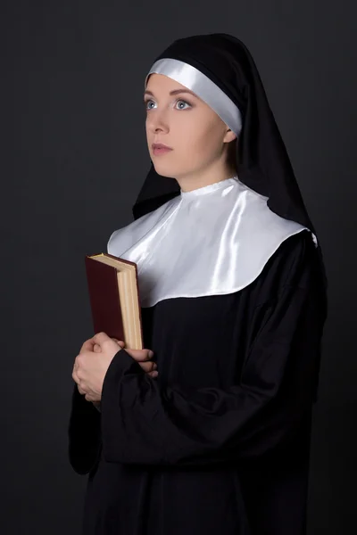 Ritratto di giovane donna suora che tiene la Bibbia sopra grey — Foto Stock