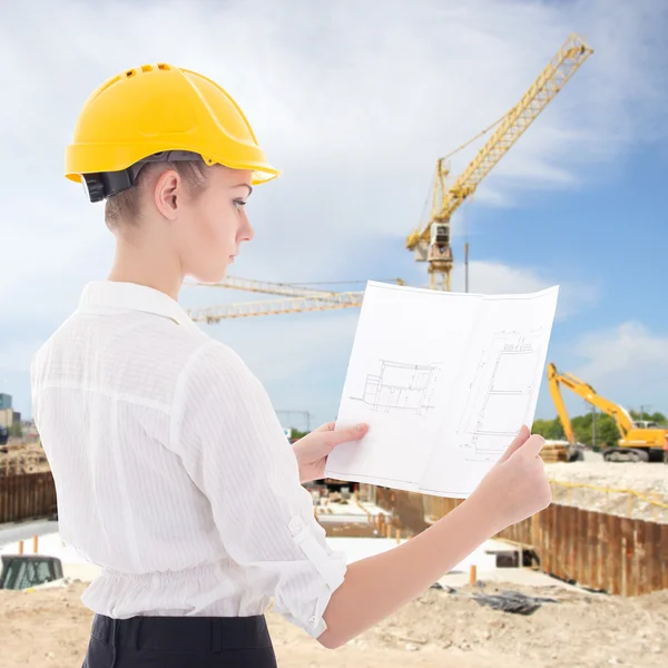 Business woman architect in yellow builder helmet with building — Stock Photo, Image