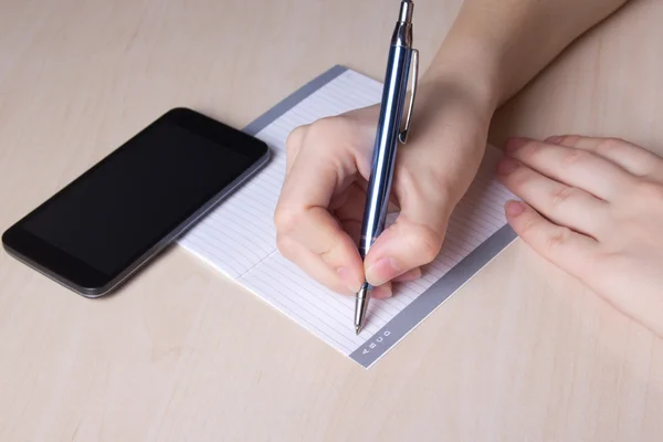 Female hand with pen, notebook and phone Stock Photo