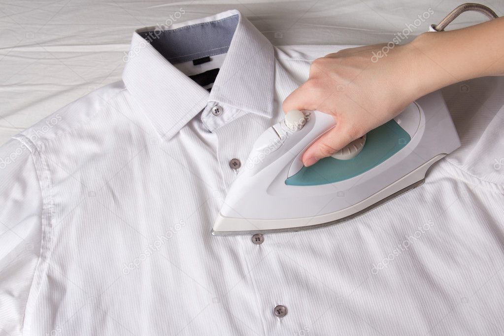 iron in female hand ironing cotton shirt