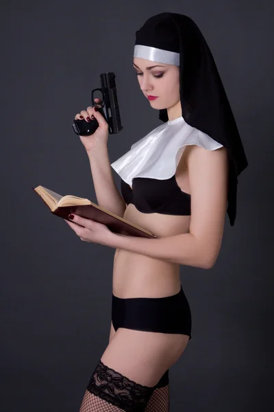 Young sexy woman in nun hat and lingerie with bible and gun over — Stock Photo, Image