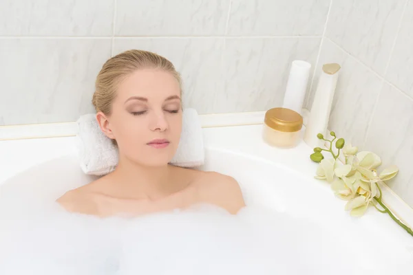 Jovem mulher deitada na banheira com espuma — Fotografia de Stock