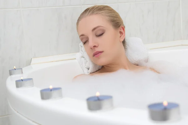 Hermosa mujer de relax en el baño con velas — Foto de Stock