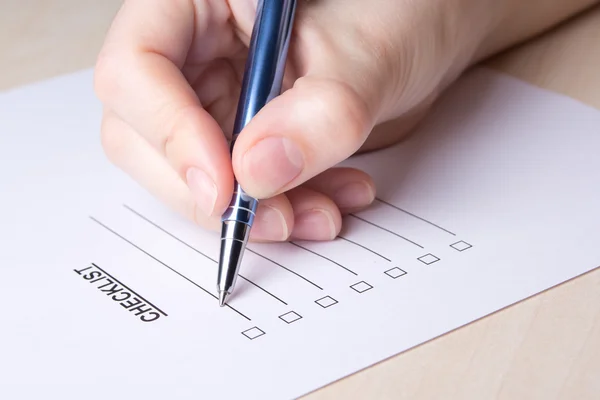 Close up of female hand filling checklist with pen — Stock Photo, Image