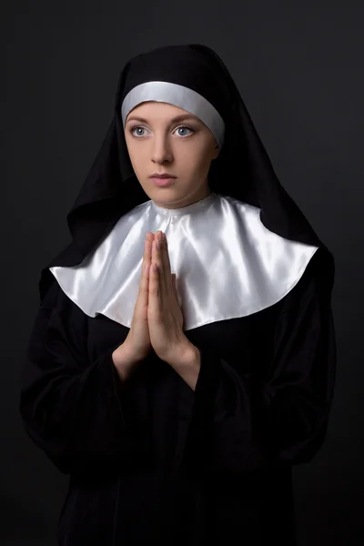 Conceito de religião - jovem bonita freira rezando sobre cinza — Fotografia de Stock