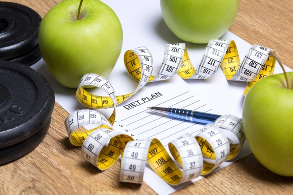Close-up de papel com o plano de dieta, maçãs, halteres e medida — Fotografia de Stock