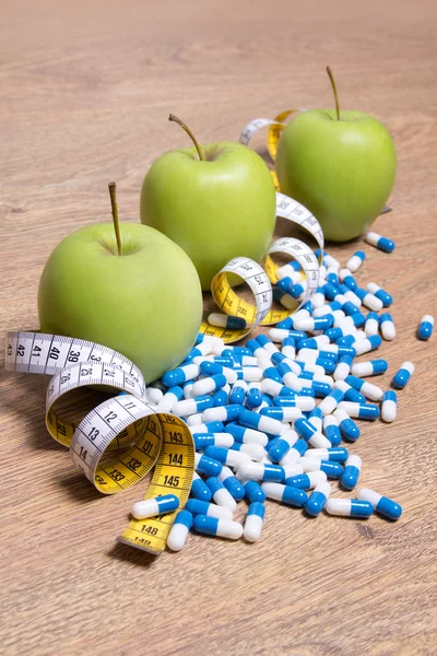 Diet concept - green apples, pills and measure tape on table — Stock Photo, Image