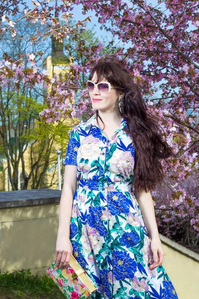 Retrato de hermosa mujer posando sobre el floreciente árbol de sakura — Foto de Stock