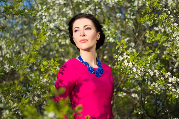 Portrait of young beautiful woman in garden with blooming trees — Stock Photo, Image