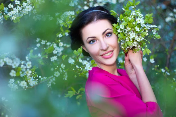 Porträtt av vacker kvinna i blommande körsbär träd trädgård — Stockfoto