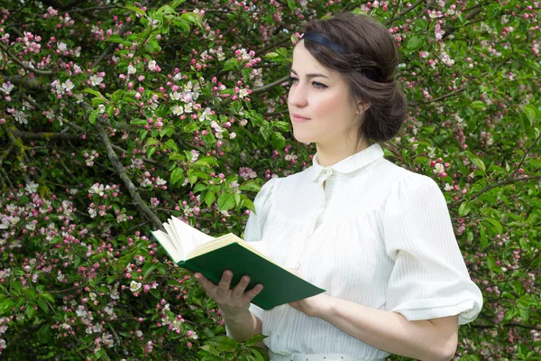 Álomszerű, szép nő olvasókönyv a virágzó tavaszi kert — Stock Fotó