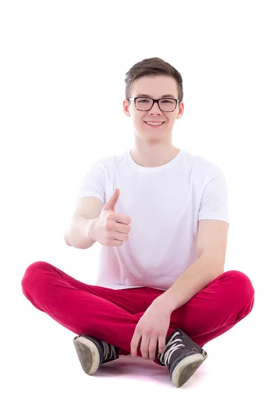 Jonge knappe man in het witte t-shirt vergadering en duimen omhoog isolat — Stockfoto
