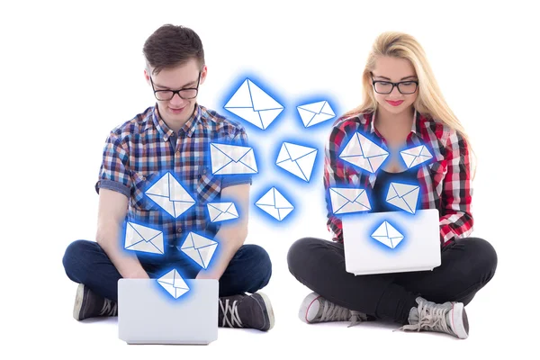 Hombre joven y mujer sentada con ordenadores portátiles y envío de mensajes es —  Fotos de Stock