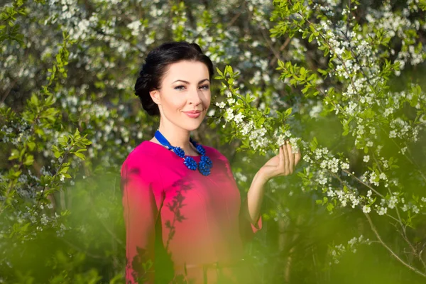 Retrato de uma jovem mulher bonita no jardim com árvores florescendo — Fotografia de Stock