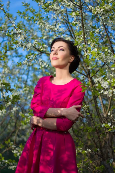 Young pretty woman in pink dress posing in blooming garden — Stock Photo, Image