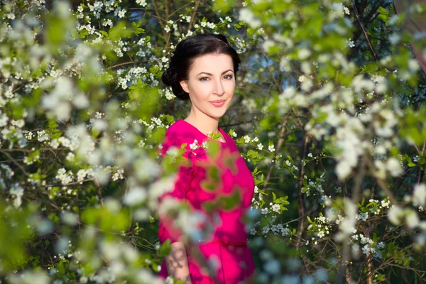 Giovane bella donna castana in piedi vicino all'albero di ciliegio — Foto Stock