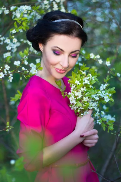 Portrait of beautiful brunette woman in pink dress in blooming c — Stock Photo, Image