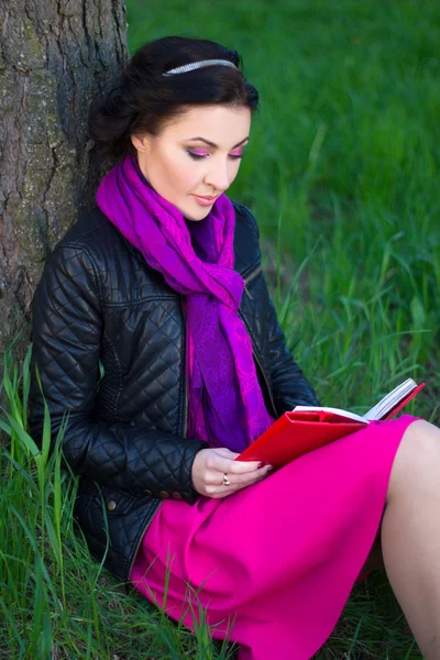Boldog szép nő a fának a közelében ült, és könyv olvasó — Stock Fotó