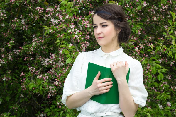 Ritratto di bella donna con il libro in fioritura giardino di primavera — Foto Stock