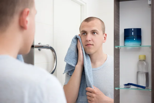 Handsome man  looking at mirror after shaving in bathroom — Stock Photo, Image