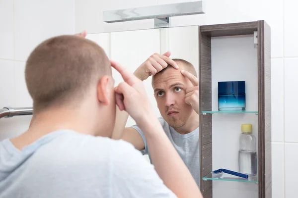 Проблема кожи концепция - человек, глядя в зеркало в ванной комнате — стоковое фото