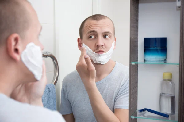 Giovane uomo bello che applica schiuma da barba in faccia — Foto Stock