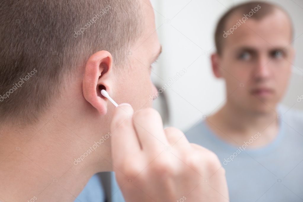man cleaning his ear with a cotton swab 