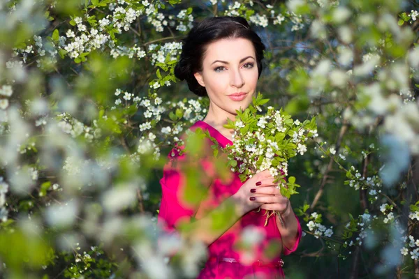 Beautiful brunette woman with blooming cherry tree — 스톡 사진