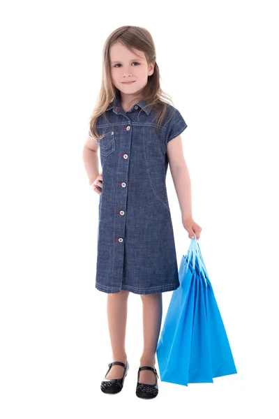 Cute little girl in denim dress with shopping bags isolated on w — Stock Photo, Image