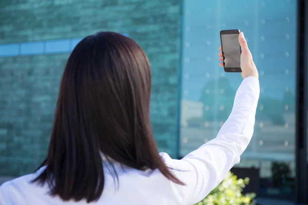 Back view of business woman making selfie photo on smartphone — Zdjęcie stockowe